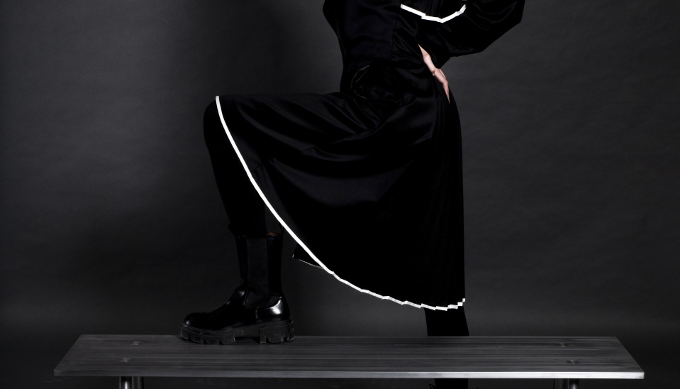 čiernych kabátových plisovaných šiat, ktoré sú inšpirované nielen stupavským krojom, ale aj príbehom o dedinských "prespálkach", ktoré boli v minulosti na okraji spoločnosti. Šaty sú doplnené úzkymi čiernymi nohavicami, ktoré podčiarkujú ženskú akcieschopnosť.  Model je doplnený šatkou kombinovanou so šiltovkou, ktoré sú interpretáciou tradičných dedinských šatiek vydatých žien na dedinách, foto: Monika Laurincová